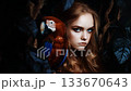 Young woman with striking blue eyes poses beside a vibrant macaw in a lush, dark setting 133670643