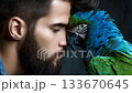 Man interacts closely with vibrant blue and green parrot, showcasing a unique bond in a serene indoor setting 133670645