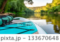 Paddleboarding on a serene river in the early evening under a tranquil sunset 133670648