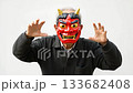 A middle-aged man wearing a red demon mask and striking a threatening pose A middle-aged man wearing a red demon mask and striking a threatening pose 133682408