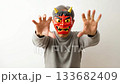 A middle-aged man wearing a demon mask makes a threatening gesture A middle-aged man wearing a demon mask makes a threatening gesture 133682409