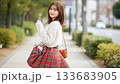 A smiling woman looking back with her skirt spread on a sidewalk lined with trees 133683905