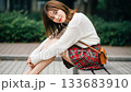 A smiling young Japanese woman sitting on a bench and looking at me 133683910