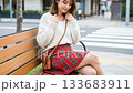 A young woman smiling shyly on a bench in the city 133683911