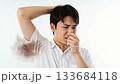 A man in a white shirt pinches his nose and grimaces, worried about his underarm odor A man in a white shirt pinches his nose and grimaces, worried about his underarm odor 133684118