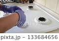 Yellow cloth is being used to clean a stove top 133684656