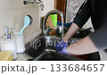 Person is washing dishes in a kitchen sink 133684657