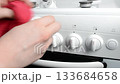 Person is adjusting the dials on a stove 133684658