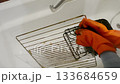 Woman is washing a dirty oven rack in a sink 133684659