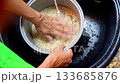 Woman rinsing rice in pot at sink 133685876