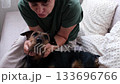 Gentle interaction Mature woman with pet dog on bed in cozy home environment moments of affection 133696766