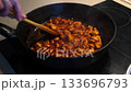 Stirring spicy chicken in a pan for a flavorful cooking experience 133696793