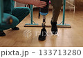physical therapy, rehabilitation center, organized space. Man with prosthetic leg receives physical therapy from medical expert, using parallel bars to help him walk in rehabilitation facility 133713280