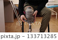 adjusting prosthetic, medical tools, support equipment. Close-up captures man seated in rehabilitation center adjusting his prosthetic leg. 133713285