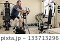 Rehabilitation workout, Press performance, Workout adaptation. Man with prosthetic leg exercises on leg press machine, surrounded by diverse gym equipment. 133713296