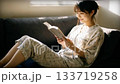 ソファーで楽しく本を読む女性 133719258