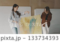 Artistic collaboration between two women showcasing a colorful painting in a studio setting Artistic collaboration between two women showcasing a colorful painting in a studio setting 133734393