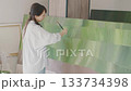 Creative woman painting a large green artwork in a bright studio Creative woman painting a large green artwork in a bright studio 133734398