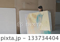 Creative woman carries large painting through art studio showcasing her dedication to the craft of painting Creative woman carries large painting through art studio showcasing her dedication to the craft of painting 133734404