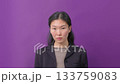 Confident woman in black blazer posing against vibrant purple background.  133759083