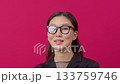 Confident young woman in glasses smiling against vibrant pink background.  133759746