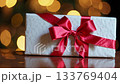 Festive gift box with red ribbon against golden bokeh lights 133769404