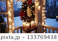 Cozy winter porch with festive wreath and twinkling lights creating holiday ambiance at dusk 133769438