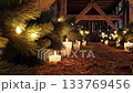Warm candlelit barn with pine branches and straw: a serene holiday atmosphere 133769456