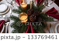 Elegant holiday table setting with pine cones and candlelight creates cozy ambiance 133769461