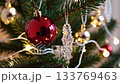 Sparkling christmas decorations: red bauble and snowflakes on pine branch with twinkling lights 133769463