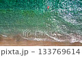 Aerial view of a man in red shorts swims in the crystal clear sea water 133769614