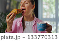 Woman enjoying a fresh croissant and coffee for breakfast. Slow motion 133770313