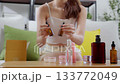 Closeup hands young asian woman cheerful holding skincare or cream sitting on sofa. 133772049