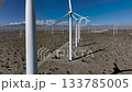 Drone rising upward over wind turbines in the San Gorgonio Pass near Palm Springs, California. Expanding aerial view of clean energy infrastructure across desert terrain. 133785005