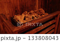 sauna stones, spa ritual, healing heat. Detail view of heated sauna stones resting on metal stove inside wooden sauna, used to generate therapeutic dry heat. 133808043