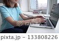 Typing on a laptop at home in the afternoon while seated near a bright window 133808226