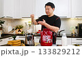 Asian man adding whey protein to blender with banana and cottage cheese preparing healthy diet shake 133829212