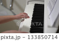 A young person practices piano at their residence. Focus is on hands moving across the keys, learning chords and melody. A study in dedication and artistic development. 133850714