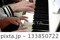 Close up of hands. A father and daughter play together on a white piano. She learns a new song. Music fills the room with joy during the early afternoon. 133850722