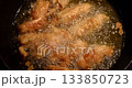 Pieces of breaded chicken sizzle in hot oil. The bubbling oil cooks the chicken to a golden brown, a flavorful dish in the making during dinner time. 133850723