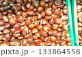 Close up view of a pile of fresh chestnuts with shiny brown shells and textured surfaces, creating a natural, organic background ideal for seasonal or food-related themes.. 133864558