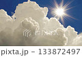 Bright Sun Shining Through Fluffy Clouds Under a Beautiful Blue Sky in a Serene Moment 133872497