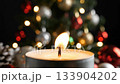Burning candle flame flickers against bokeh Christmas lights before being blown out while candle emits swirling smoke; festive candle creates magical holiday atmosphere in dark room concept. 133904202