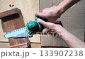 Closeup of a person operating a small electric saw on wood, showcasing precision and craftsmanship. Perfect for illustrating DIY projects, woodworking, and power tools. 133907238