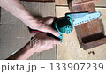 Closeup view of hands operating a small chainsaw. Implies precision, home improvement, crafting, or DIY projects. Good for illustrating woodworking, tools, and skills. 133907239
