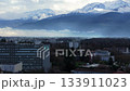 Urban panorama showcasing Grenoble Hospital nestled against snow crowned Belledonne mountains during luminous winter daylight. May 4th 2024 133911023