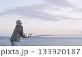 A handsome blond boy is standing with a fishing rod by the sea and fishing 133920187
