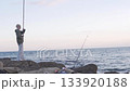 Handsome blond boy fishing with a fishing rod on a rock by the sea 133920188