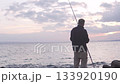 A man with a fishing rod is standing by the seashore and fishing 133920190