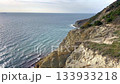 Scenic view of rugged cliffs meeting calm ocean waters, highlighting textures of rocks and waves, with a smooth camera zoom enhancing the serene atmosphere 133933218